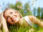 Happy girl dreaming in a grass with flowers
