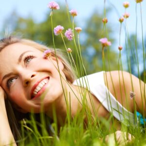 Happy girl dreaming in a grass with flowers