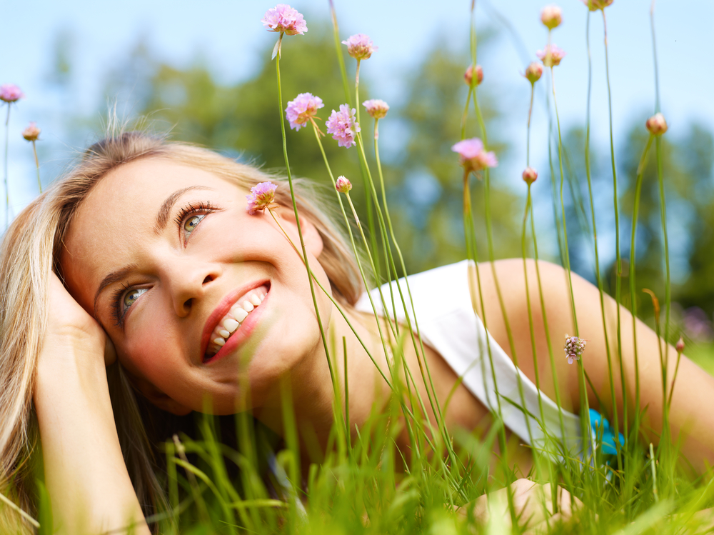 Happy girl dreaming in a grass with flowers