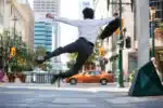 Rear view of business man jumping in air and kicking heals
