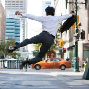 Rear view of business man jumping in air and kicking heals