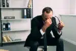 man sitting on a stool in a suit looking stressed