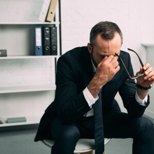 man sitting on a stool in a suit looking stressed