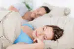 Young couple sleeping in bed having a restful sleep, closeup of the wife.